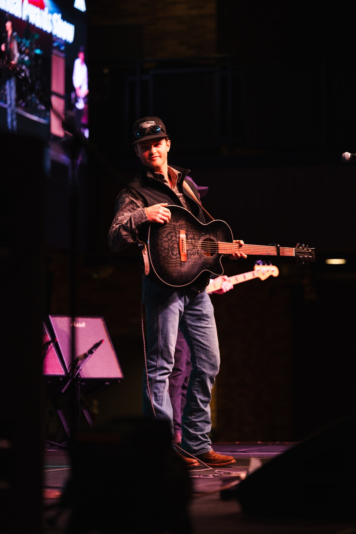 Jordan Paddock with his guitar on stage